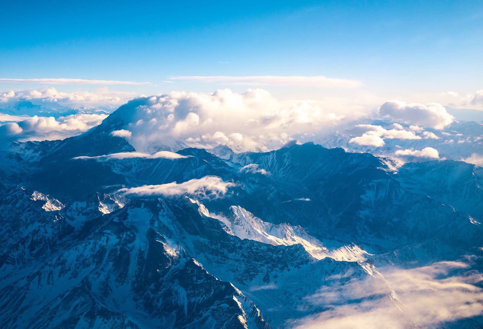 Aerial view of the Andes' snow-capped peaks rising above the clouds